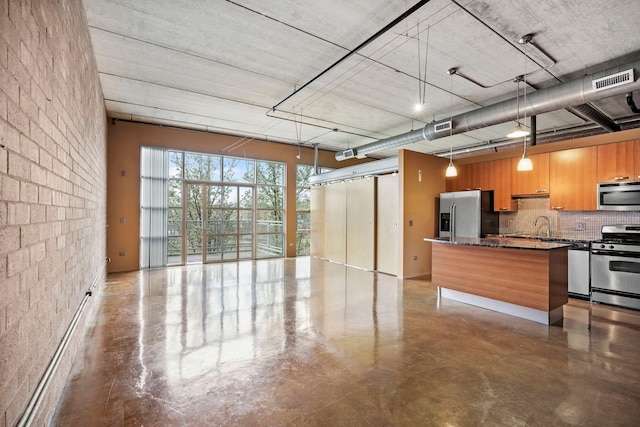 kitchen featuring stainless steel appliances, open floor plan, backsplash, finished concrete flooring, and hanging light fixtures