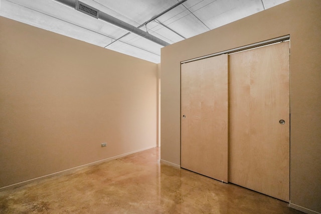 unfurnished bedroom featuring finished concrete floors and a closet