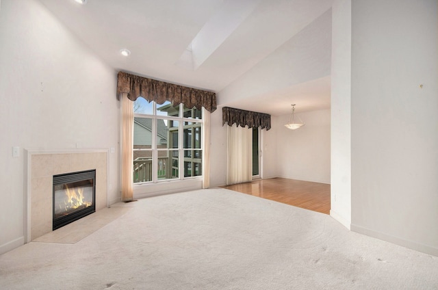 unfurnished living room with carpet, a fireplace, vaulted ceiling, and baseboards
