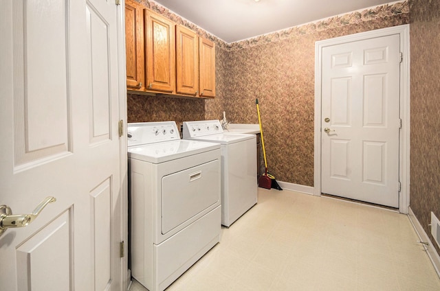 laundry room featuring cabinet space, washing machine and clothes dryer, wallpapered walls, light floors, and baseboards