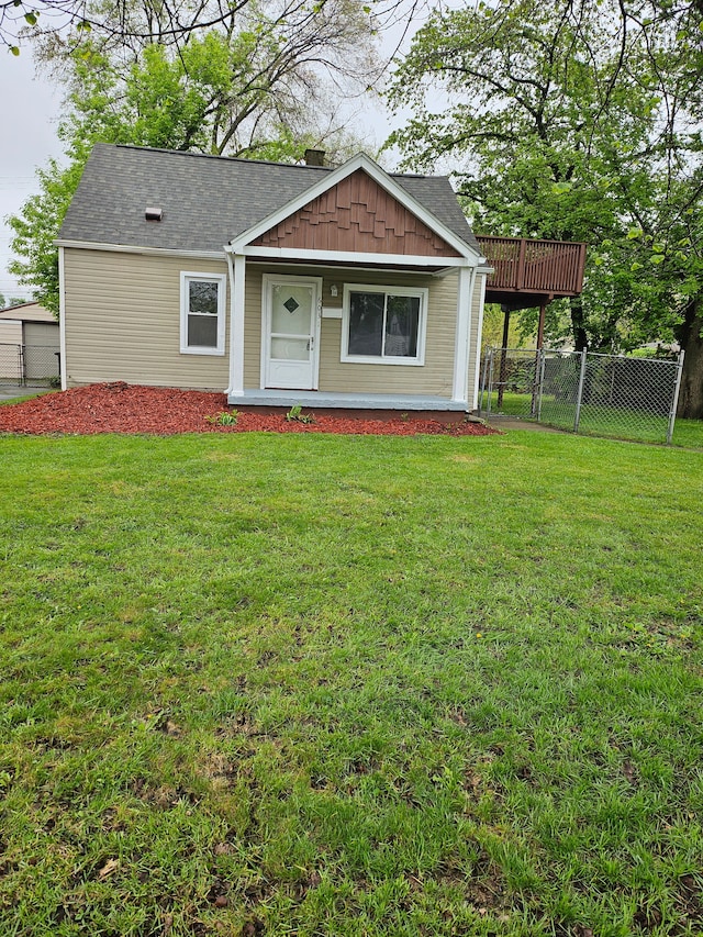 view of front facade featuring covered porch, a front yard, a shingled roof, and fence