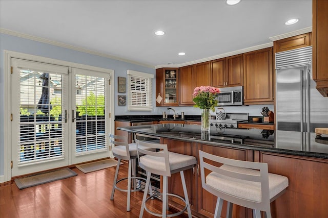 kitchen with stainless steel appliances, crown molding, recessed lighting, brown cabinetry, and wood finished floors
