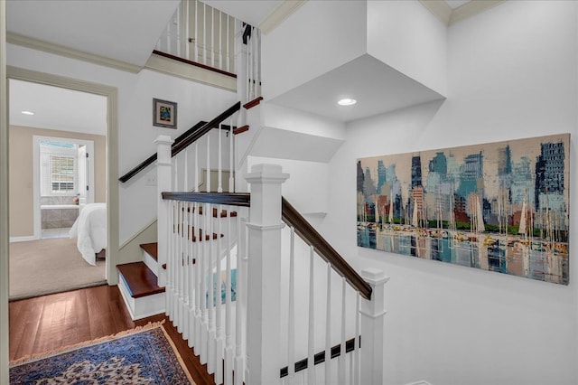 stairway featuring wood finished floors and ornamental molding