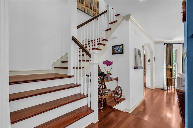 stairs with wood finished floors, baseboards, and ornamental molding