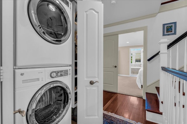 laundry area with stacked washer / drying machine, wood finished floors, and baseboards