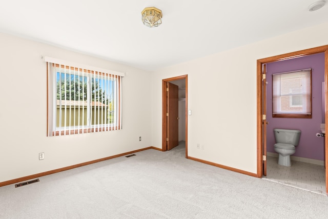 unfurnished bedroom featuring baseboards, a spacious closet, carpet flooring, and visible vents