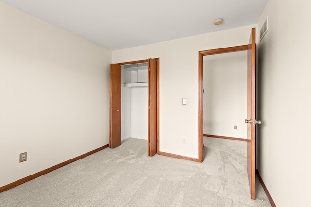 unfurnished bedroom featuring light colored carpet, baseboards, a closet, and visible vents