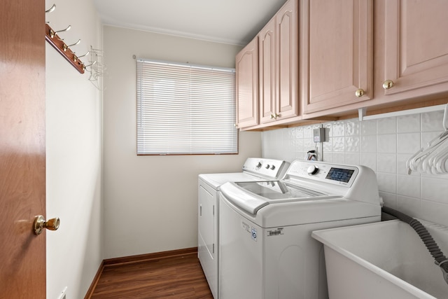 laundry area featuring a sink, cabinet space, dark wood finished floors, washing machine and dryer, and baseboards
