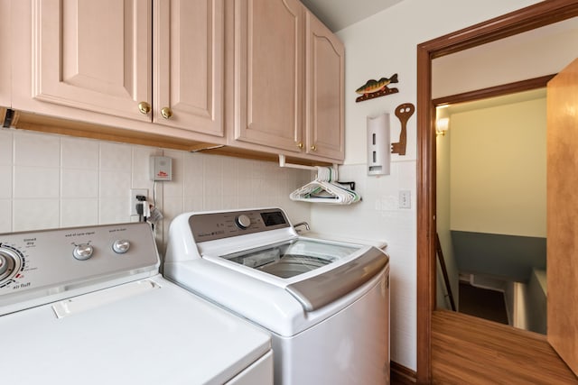 clothes washing area featuring separate washer and dryer and cabinet space