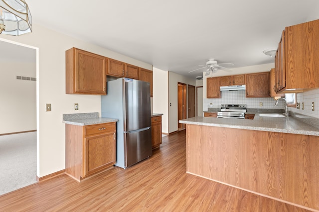 kitchen with a ceiling fan, a sink, stainless steel appliances, under cabinet range hood, and light wood-style floors