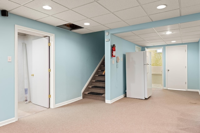 below grade area with freestanding refrigerator, stairway, baseboards, light carpet, and recessed lighting