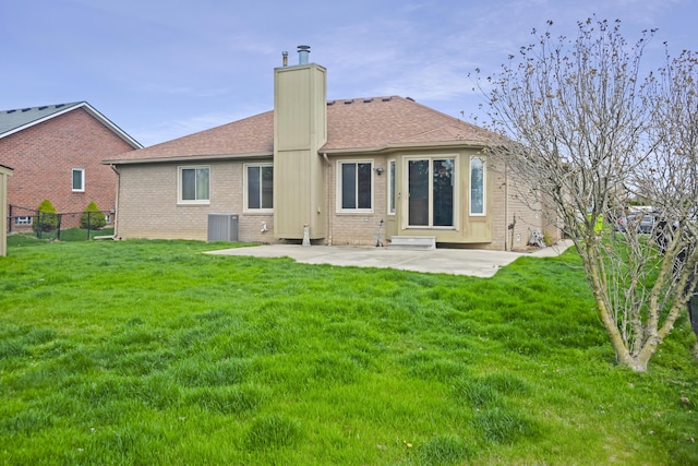 rear view of property featuring a patio area, fence, brick siding, a yard, and a chimney