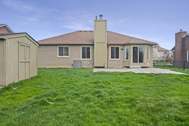 rear view of house with a lawn, brick siding, fence, a patio area, and a storage unit