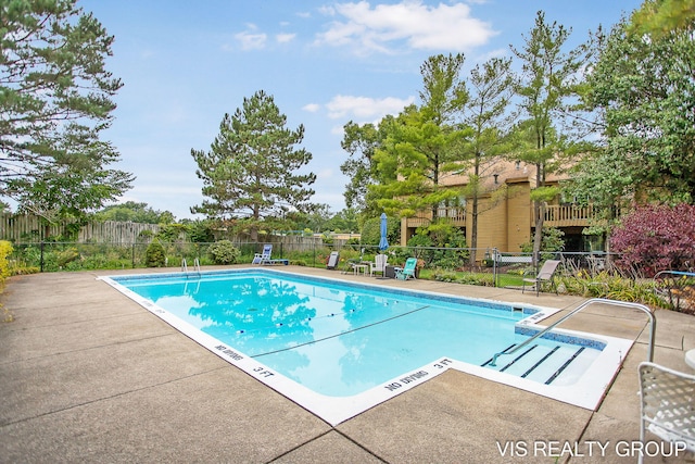 pool with a patio area and fence