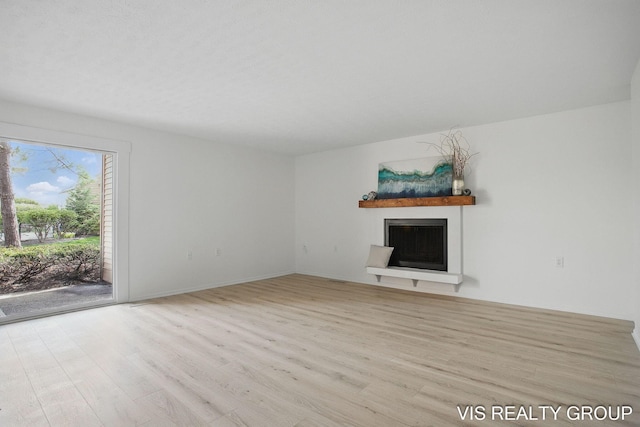 unfurnished living room featuring wood finished floors and a fireplace with raised hearth