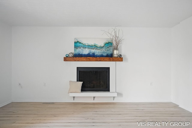 room details featuring baseboards, wood finished floors, a fireplace, and visible vents