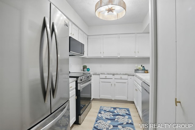 kitchen featuring light wood finished floors, stainless steel appliances, and white cabinetry