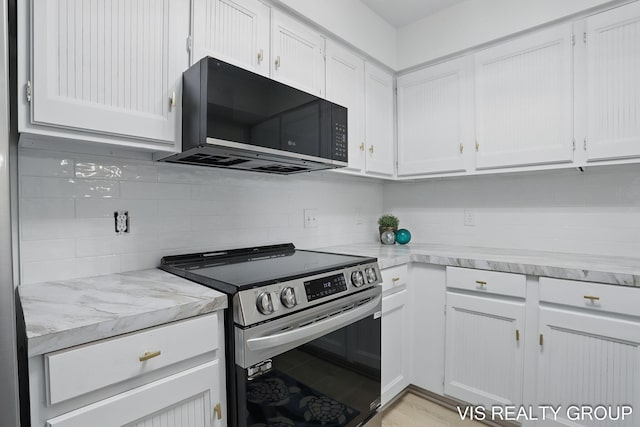 kitchen featuring tasteful backsplash, black microwave, white cabinets, and electric stove