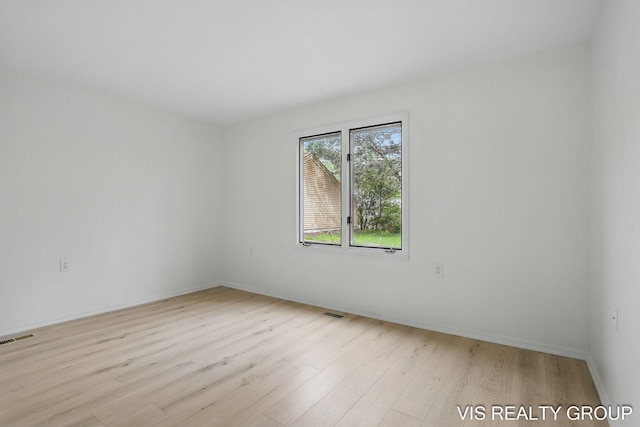 empty room featuring baseboards, visible vents, and wood finished floors