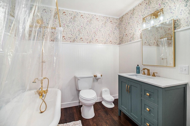 bathroom featuring toilet, a wainscoted wall, wood finished floors, a soaking tub, and wallpapered walls