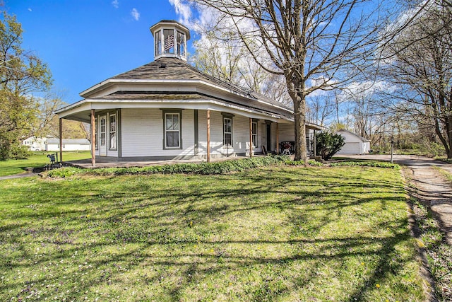 exterior space featuring covered porch, an outdoor structure, and a front lawn