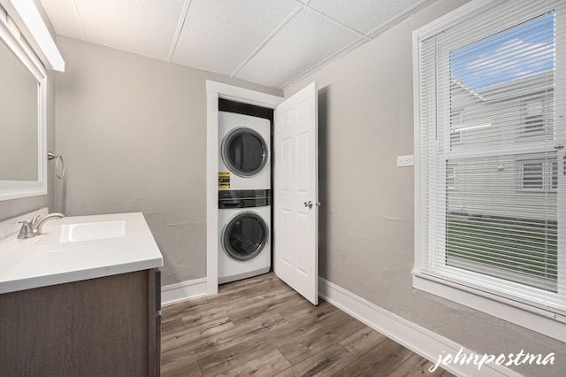 1108/1110 Muskegon Ave NW, Grand Rapids, MI 49504 - washroom with stacked washer / dryer, wood finished floors, a sink, laundry area, and baseboards
