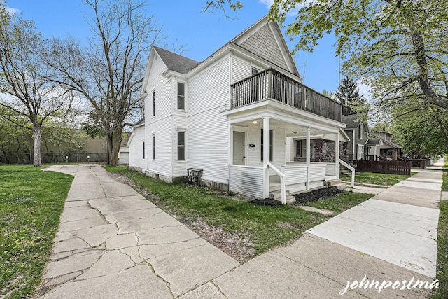1108/1110 Muskegon Ave NW, Grand Rapids, MI 49504 - view of front facade featuring covered porch, a shingled roof, a front lawn, and a balcony