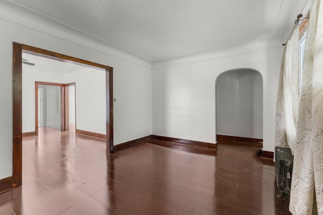 empty room featuring baseboards and arched walkways
