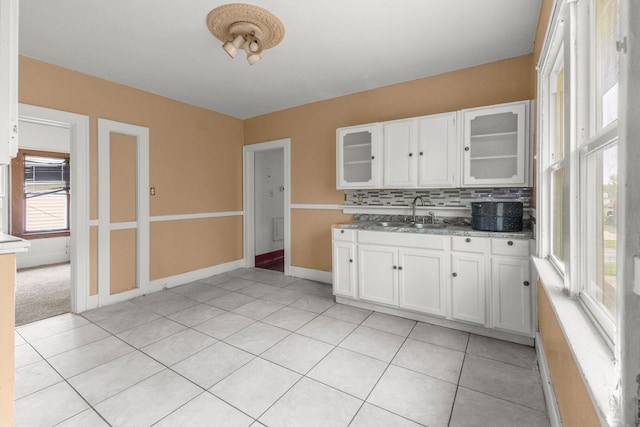 kitchen featuring white cabinets, backsplash, glass insert cabinets, and a sink