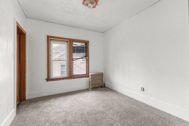 spare room featuring carpet, a textured ceiling, baseboards, and radiator heating unit