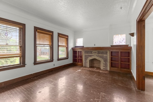 unfurnished living room with a wealth of natural light, hardwood / wood-style floors, a fireplace with flush hearth, and a textured ceiling