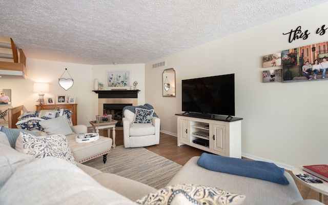 6480 Scenic Pines Ct, Clarkston, MI 48346 - living area with wood finished floors, a tile fireplace, a textured ceiling, and baseboards