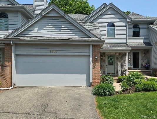 6480 Scenic Pines Ct, Clarkston, MI 48346 - view of front of home with an attached garage, brick siding, a chimney, and asphalt driveway