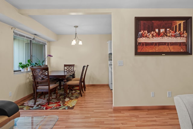 dining area with light wood finished floors, baseboards, and an inviting chandelier