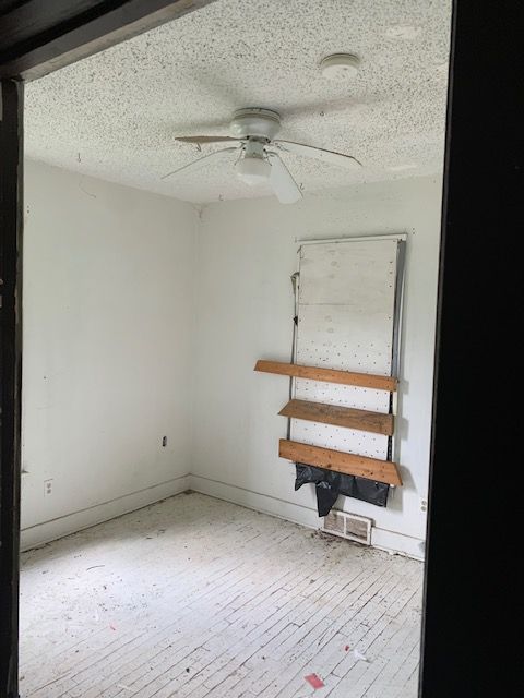 spare room featuring a textured ceiling, baseboards, a ceiling fan, and wood-type flooring