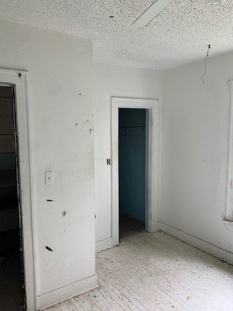 unfurnished room with light wood finished floors and a textured ceiling