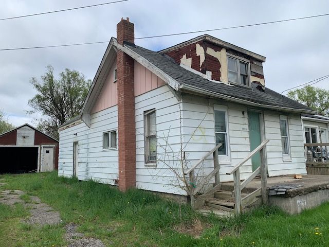view of home's exterior with roof with shingles, an outdoor structure, and a chimney