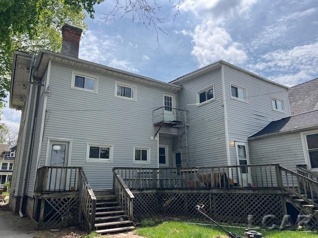 back of house featuring stairway, a wooden deck, and a chimney