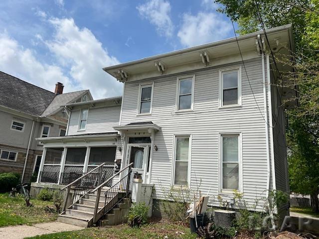 italianate-style house featuring central AC unit and a sunroom