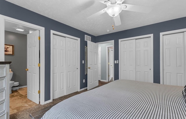 bedroom with visible vents, baseboards, a ceiling fan, and multiple closets