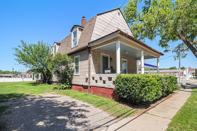 view of home's exterior with a porch, a chimney, and a lawn