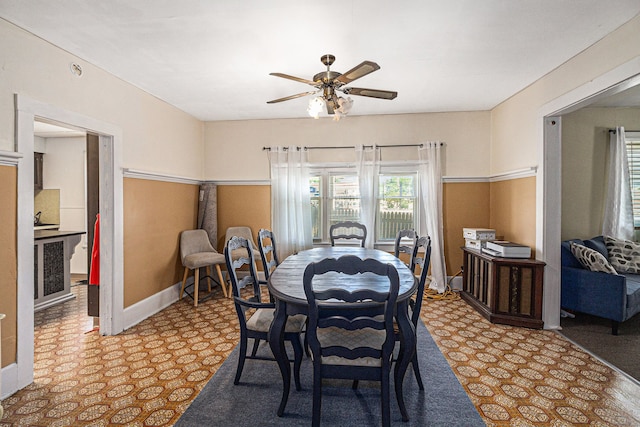 dining space with a ceiling fan and baseboards