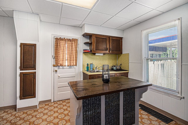 kitchen with butcher block countertops, a drop ceiling, open shelves, tasteful backsplash, and dark brown cabinets