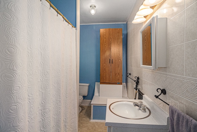 bathroom with toilet, crown molding, vanity, and tile walls