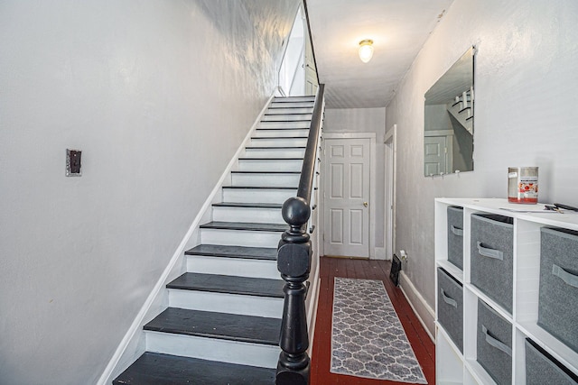 staircase featuring wood finished floors and baseboards