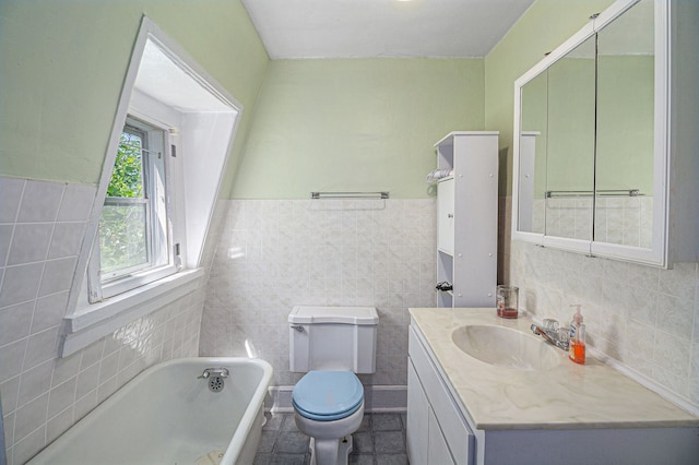 bathroom featuring tile walls, a bath, toilet, vanity, and wainscoting