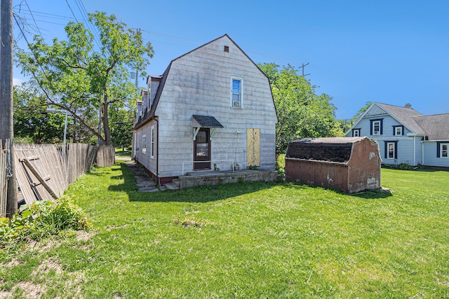 back of house featuring a gambrel roof, a storage shed, and an outbuilding