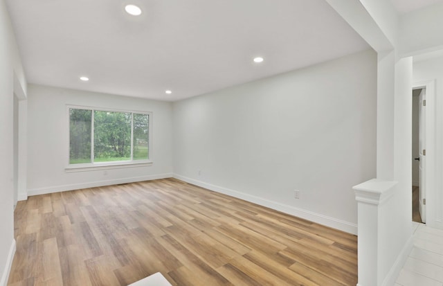 empty room with light wood finished floors, recessed lighting, and baseboards