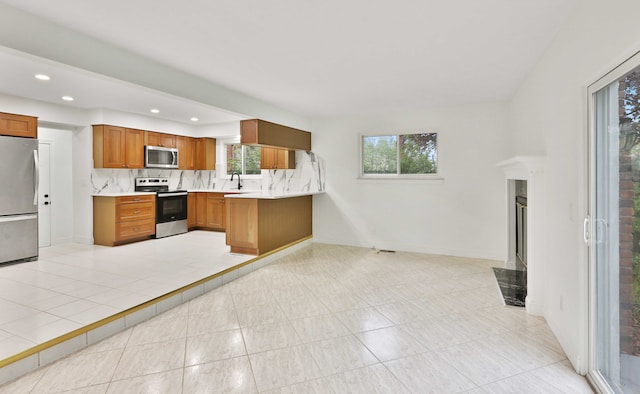 kitchen featuring stainless steel appliances, brown cabinets, a sink, light countertops, and tasteful backsplash