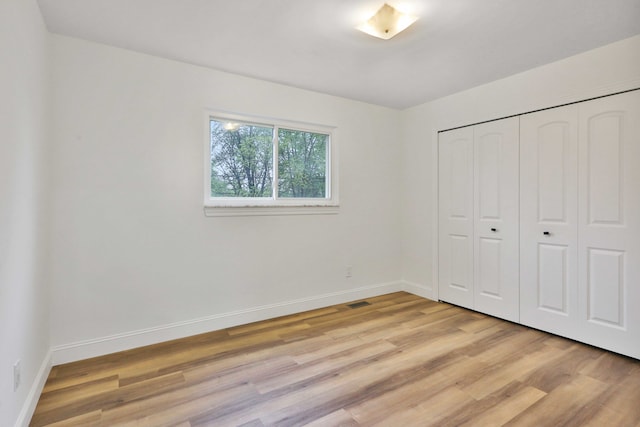 unfurnished bedroom with light wood-style floors, baseboards, and a closet